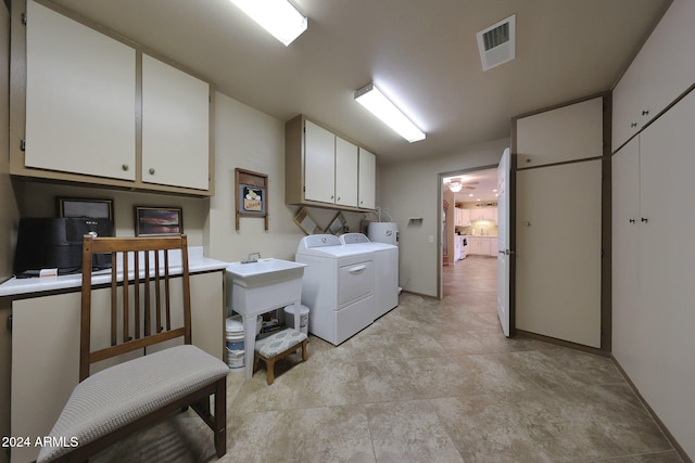 clothes washing area featuring washing machine and clothes dryer, sink, and cabinets