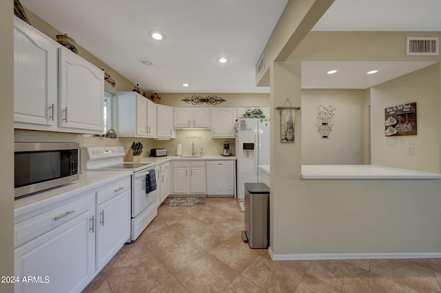 kitchen with white appliances, white cabinets, sink, and kitchen peninsula