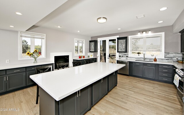 kitchen featuring stainless steel appliances, decorative backsplash, a center island, and light hardwood / wood-style flooring