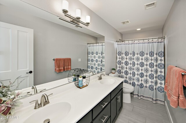 bathroom with tile patterned flooring, double sink vanity, and toilet