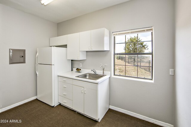 kitchen with sink, white refrigerator, dark carpet, electric panel, and white cabinetry