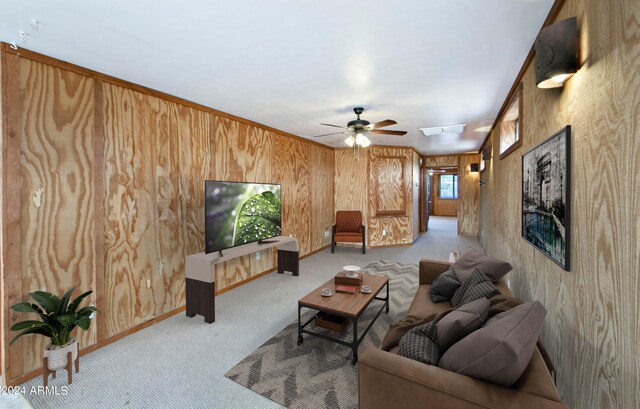 carpeted living room featuring wood walls and ceiling fan