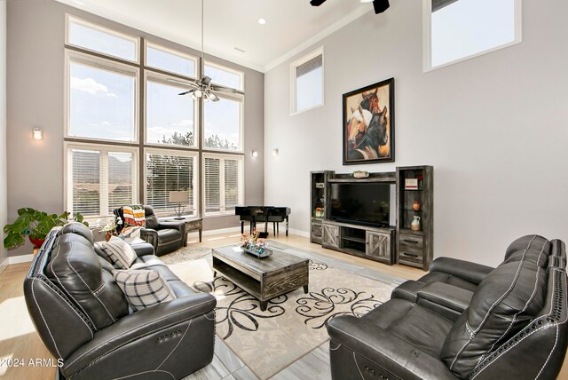 living room with plenty of natural light, ceiling fan, and a towering ceiling