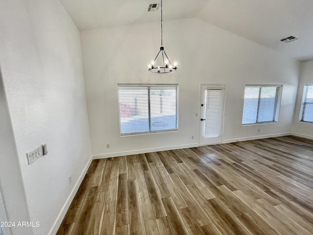 interior space with wood-type flooring, high vaulted ceiling, and an inviting chandelier