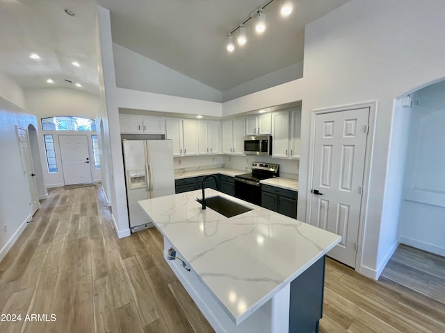 kitchen with a center island, sink, light stone countertops, light hardwood / wood-style floors, and stainless steel appliances