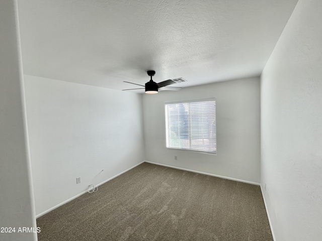 unfurnished room with dark colored carpet and ceiling fan