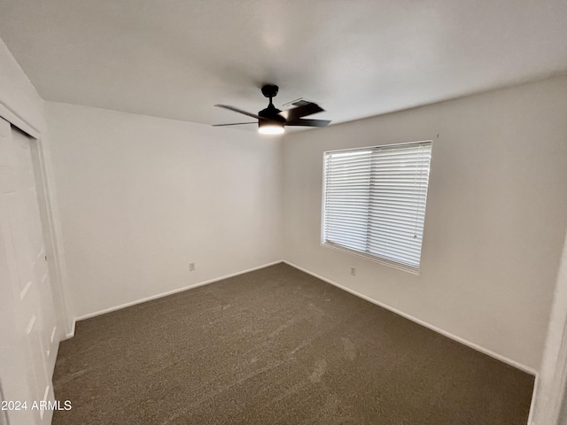 unfurnished bedroom with ceiling fan and dark carpet