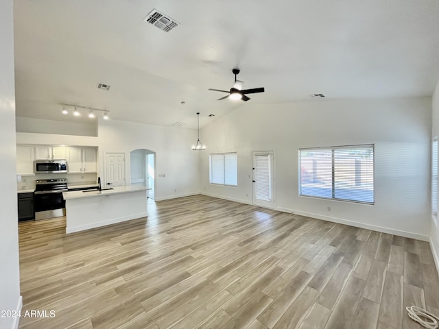 unfurnished living room with ceiling fan, sink, light hardwood / wood-style floors, and vaulted ceiling