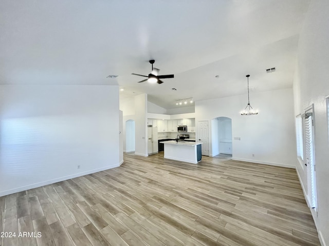 unfurnished living room featuring ceiling fan with notable chandelier, vaulted ceiling, and light hardwood / wood-style flooring