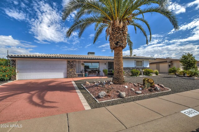 ranch-style home with an attached garage, stone siding, a tile roof, and concrete driveway