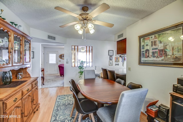 dining room with a textured ceiling, light hardwood / wood-style flooring, and ceiling fan