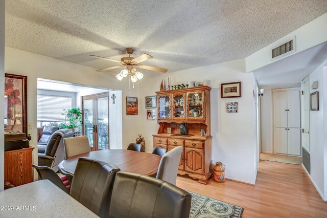 dining area with light wood-type flooring, a textured ceiling, and ceiling fan