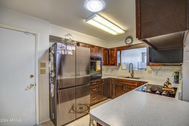 kitchen featuring light countertops, a sink, black appliances, and light tile patterned flooring