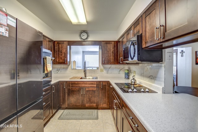 kitchen with appliances with stainless steel finishes, light tile patterned flooring, sink, and decorative backsplash