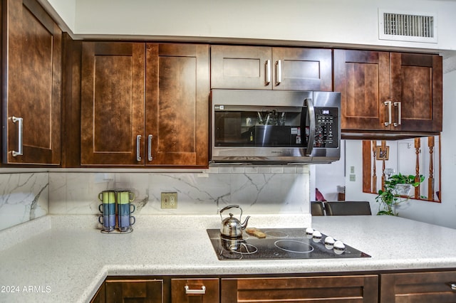 kitchen with black electric cooktop, dark brown cabinetry, and backsplash