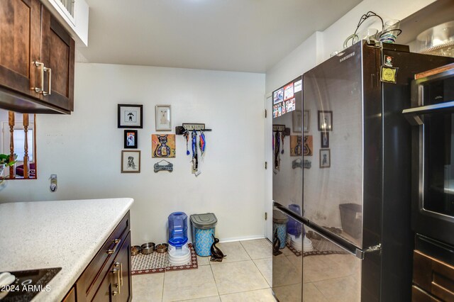 kitchen with black electric stovetop, light tile patterned flooring, light countertops, and freestanding refrigerator