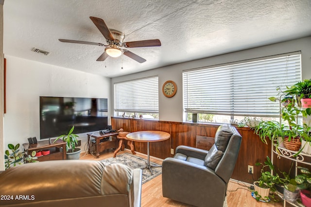 living room featuring a textured ceiling, wood-type flooring, and ceiling fan