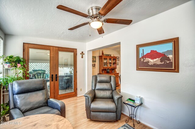 living area with light wood-type flooring, a textured ceiling, a wealth of natural light, and ceiling fan