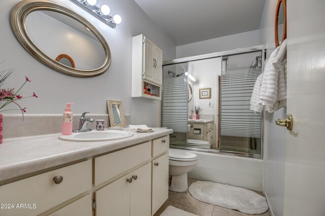 full bathroom with tile patterned flooring, enclosed tub / shower combo, toilet, and vanity