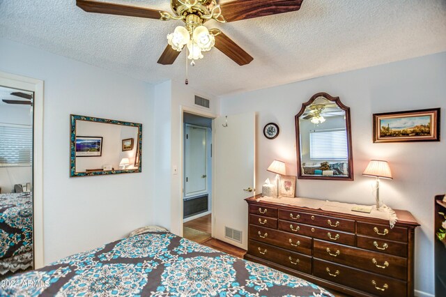 bedroom with a textured ceiling, visible vents, and wood finished floors