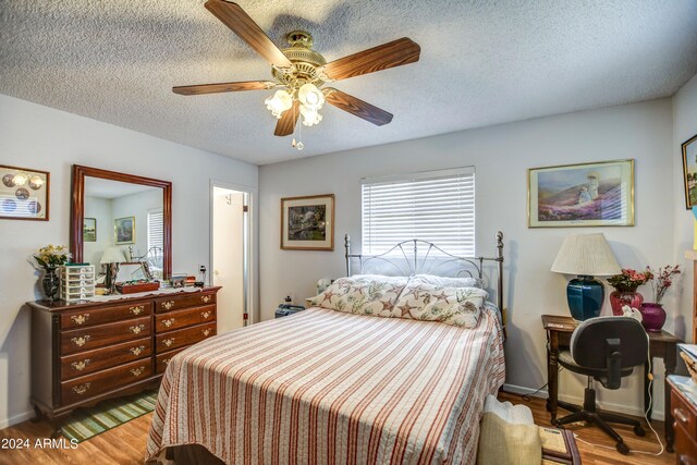 bedroom with a textured ceiling, ceiling fan, and light hardwood / wood-style floors