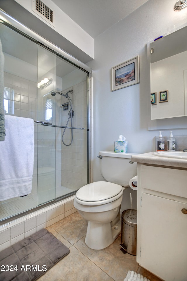 bathroom with tile patterned flooring, vanity, toilet, and walk in shower