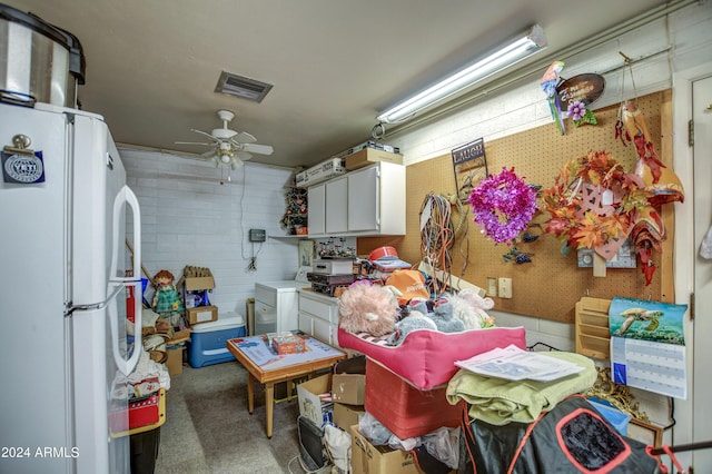 interior space featuring ceiling fan, visible vents, freestanding refrigerator, washer / clothes dryer, and concrete block wall