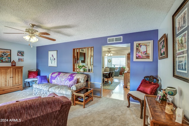 living room featuring ceiling fan, light carpet, and a textured ceiling