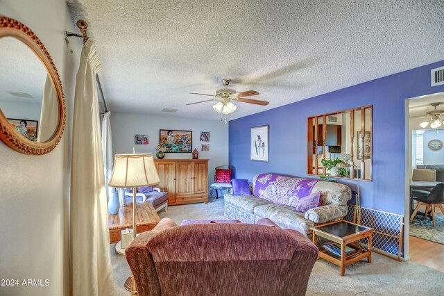 carpeted living room with ceiling fan and a textured ceiling