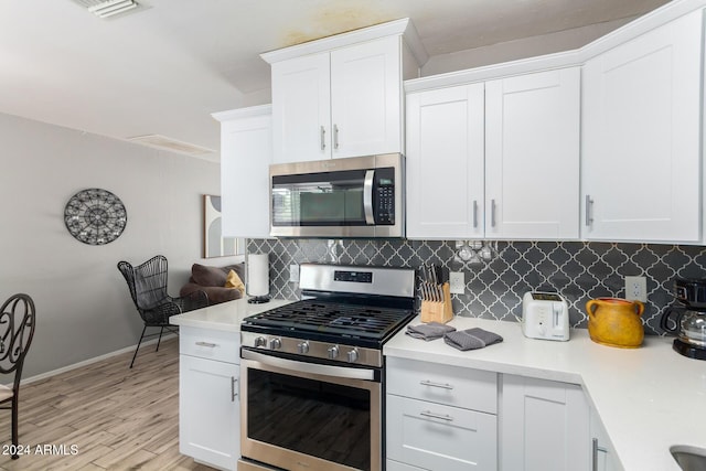 kitchen featuring white cabinets, appliances with stainless steel finishes, and backsplash