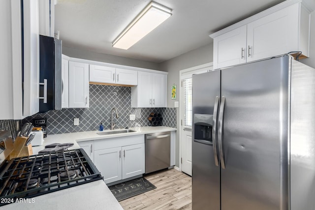 kitchen featuring sink, light hardwood / wood-style flooring, tasteful backsplash, white cabinetry, and stainless steel appliances