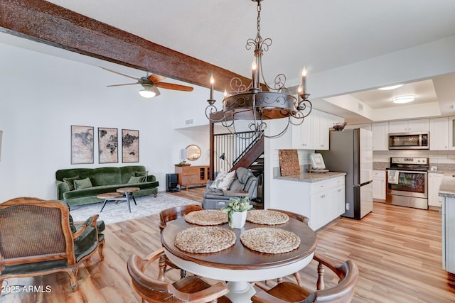 dining space featuring light wood finished floors, visible vents, beamed ceiling, stairway, and a ceiling fan