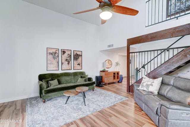 living area with stairway, wood finished floors, visible vents, and baseboards