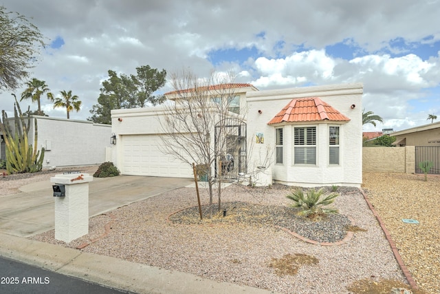 mediterranean / spanish house with stucco siding, fence, concrete driveway, a garage, and a tiled roof