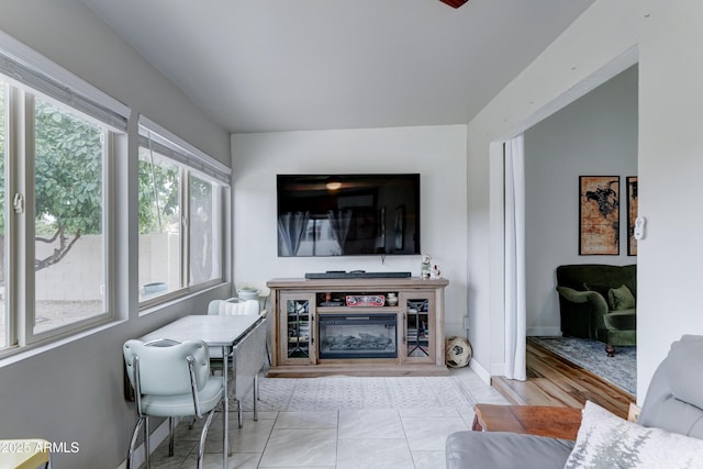 living room featuring tile patterned floors, baseboards, and a glass covered fireplace