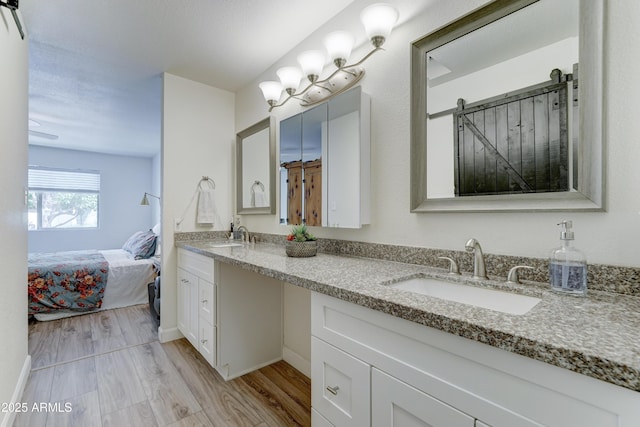 ensuite bathroom with double vanity, wood finished floors, ensuite bathroom, and a sink