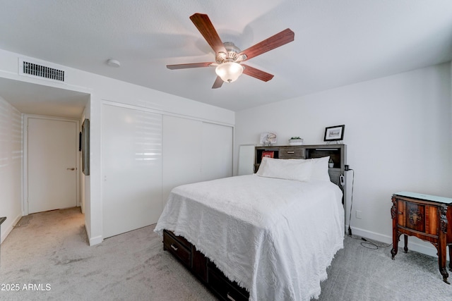 bedroom with visible vents, baseboards, ceiling fan, light carpet, and a closet