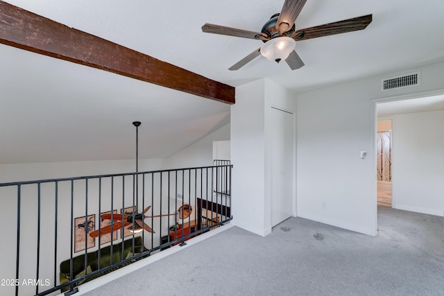 carpeted empty room with baseboards, visible vents, vaulted ceiling with beams, and ceiling fan