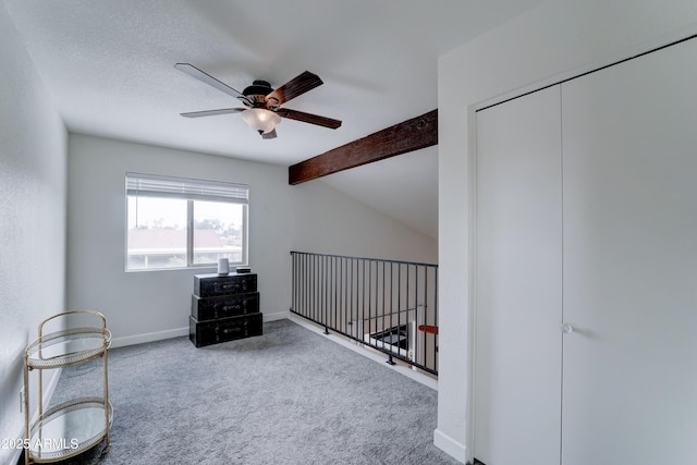 interior space with baseboards, lofted ceiling with beams, carpet floors, a textured ceiling, and a ceiling fan