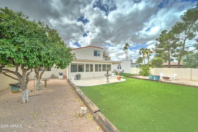 rear view of house featuring a fire pit, stucco siding, a fenced backyard, a yard, and a patio area