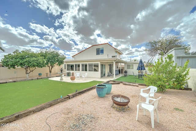 rear view of house featuring a fenced backyard, stucco siding, a fire pit, a patio area, and a lawn