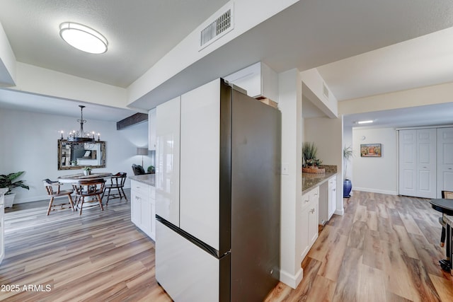 kitchen featuring visible vents, light stone countertops, light wood-style floors, and white cabinetry