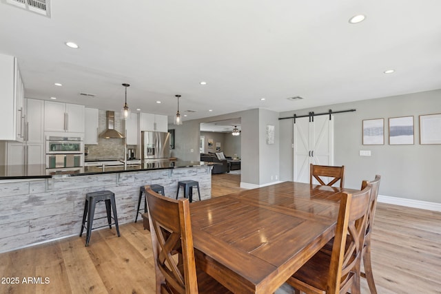 dining area featuring visible vents, a barn door, recessed lighting, and light wood-type flooring