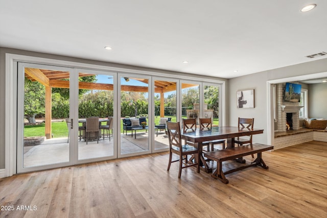 dining area featuring a brick fireplace, recessed lighting, visible vents, and light wood-type flooring