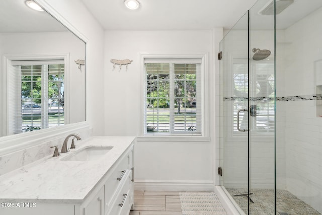 bathroom featuring baseboards, a shower stall, a wealth of natural light, and vanity