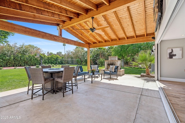 view of patio featuring a ceiling fan, outdoor dining area, and an outdoor living space with a fireplace