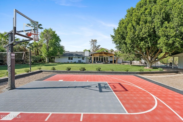 view of sport court with basketball hoop and a lawn