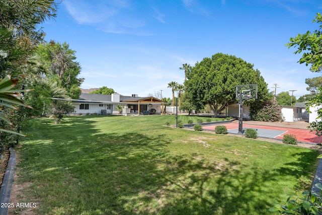 view of yard featuring basketball court and fence