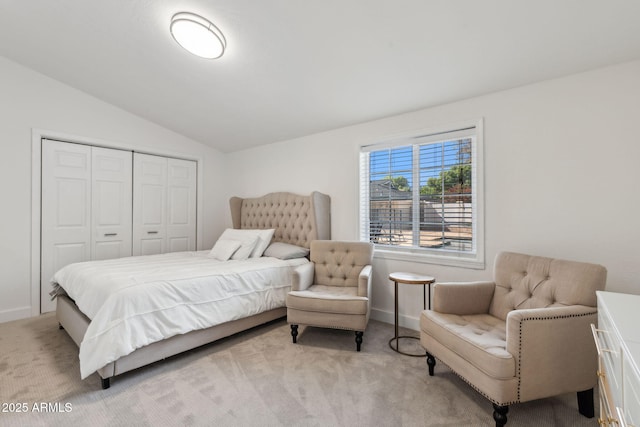 bedroom featuring a closet, baseboards, vaulted ceiling, and light carpet