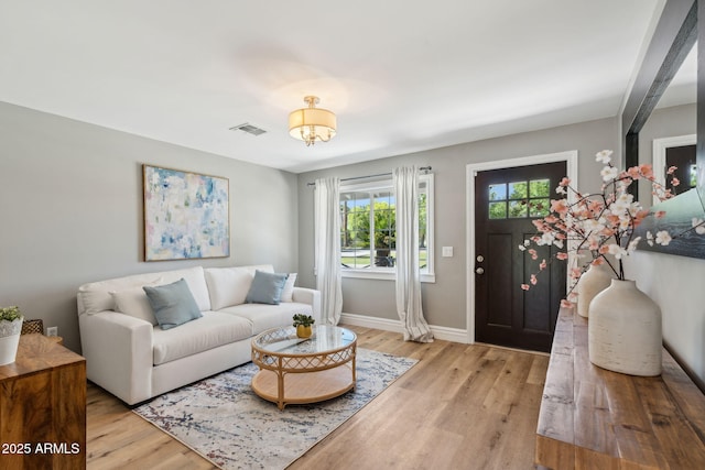 living room with baseboards, visible vents, and light wood-style floors